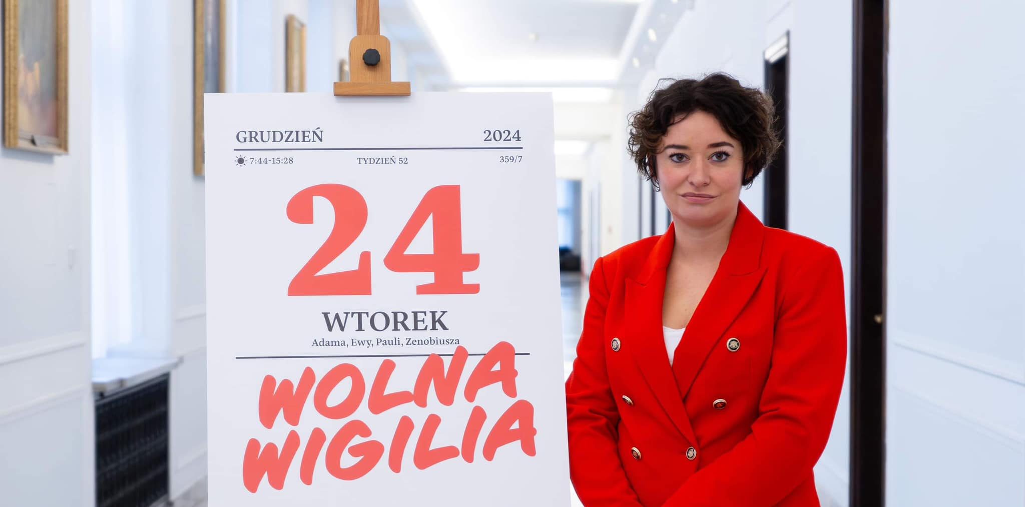 Posłanka Lewicy Anna-Maria Żukowska stoi obok dużej planszy z datą 24 grudnia 2024 i napisem "Wolna Wigilia".