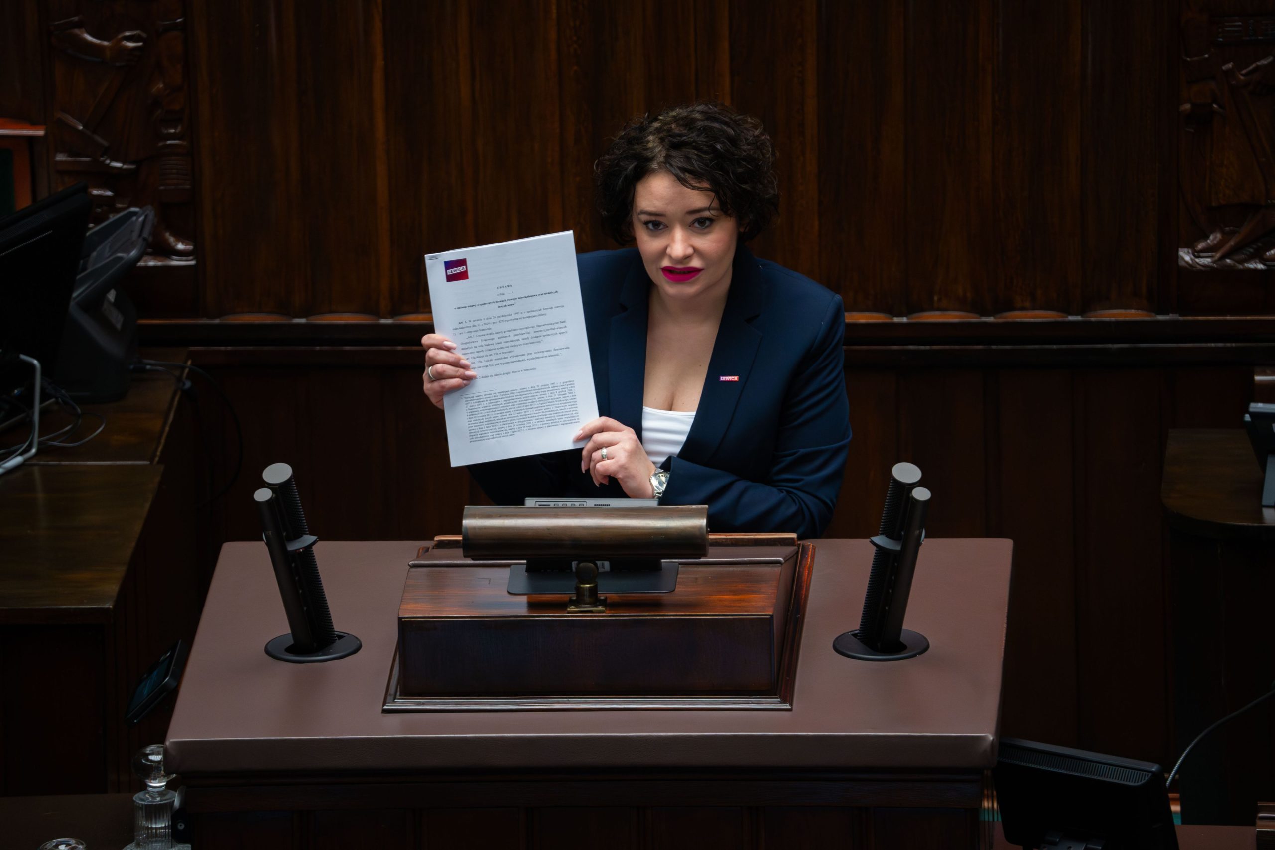 Posłanka Żukowska podczas wystąpienia w sejmie pokazuje dokument projektu ustawy.