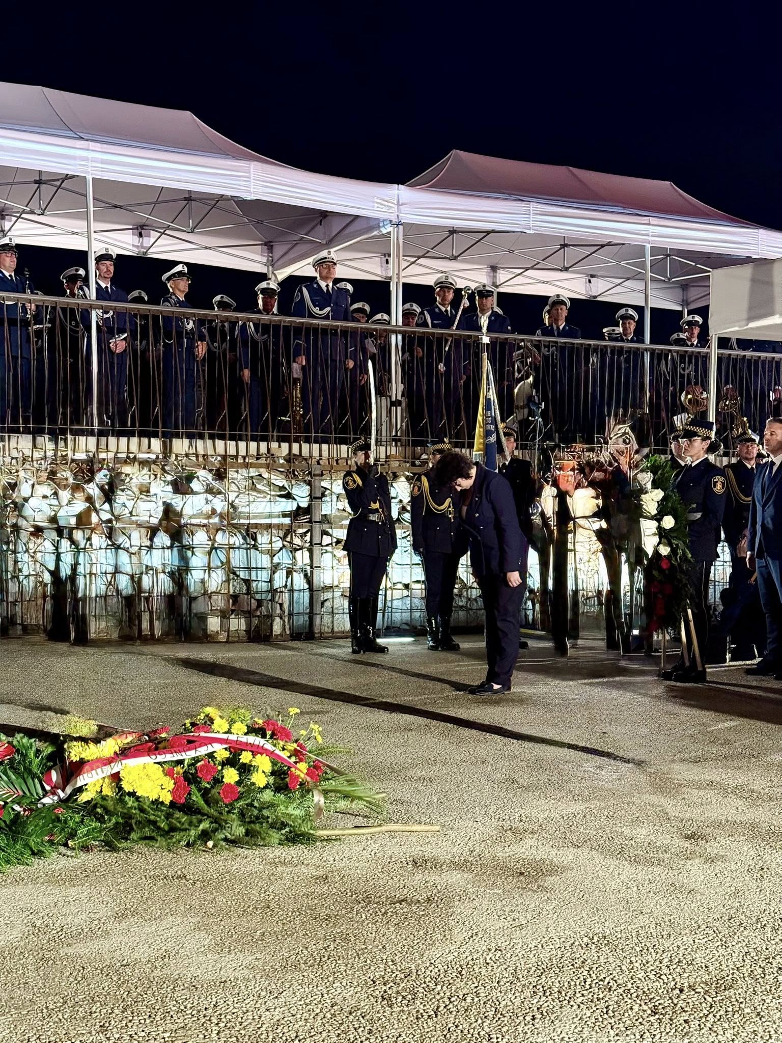Uroczystości upamiętniające Powstanie Warszawskie na Kopcu Powstania Warszawskiego podczas wieczornego apelu z udziałem umundurowanych żołnierzy i składania kwiatów.