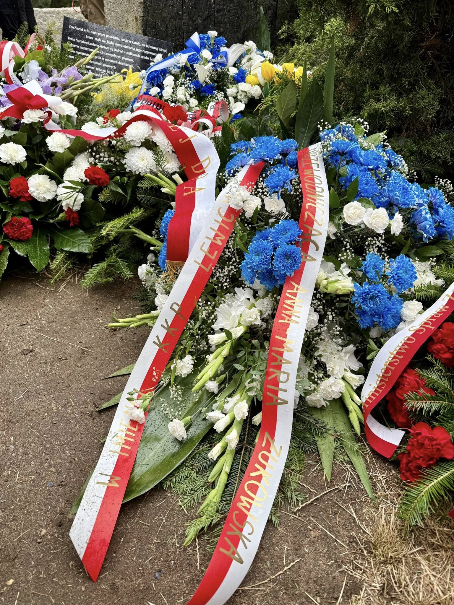 Wieniec i kwiaty z biało-czerwonymi kokardami na miejscu pamięci ofiar tragedii w Jedwabnem.