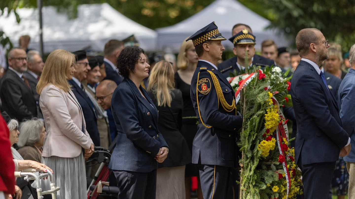 Uczestnicy uroczystości patriotycznej oddają hołd bohaterom, składając wieńce i stojąc w skupieniu.